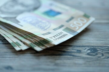 Many five hundred hryvnia money bills lies on wooden background. Ukrainian national currency close...