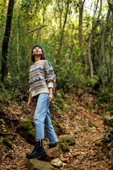 woman in a sweater and a backpack on her back travels. on a hike in the mountains. Young happy tourist woman relaxing in nature