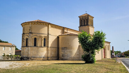 Roman church of Grayan, Medoc, Nouvelle-Aquitaine, Southwest of France. In the foreground - a green tree in the form of a heart.