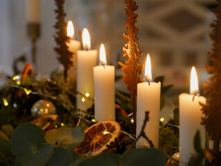 Christmas decoration inspiration. Candles on the table. Table arrangement and setting. Green moss, eucalyptus and dried oranges. Candle holders. Burning flames. Christmas celebration and interior.