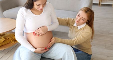 Young pregnant woman with doula sitting on fitball at home