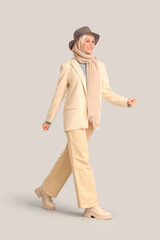 Beautiful young happy Muslim woman in hijab with stylish hat on grey background