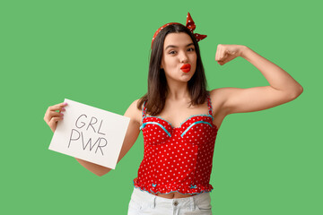 Beautiful young happy pin-up woman holding paper sheet with text GIRL POWER and showing muscles on...