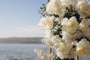 White roses and gypsophila decorating wedding altar overlooking lake