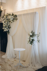 Elegant white wedding decorations with floral arrangements and white curtain backdrop
