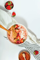 Smoothie bowl topped with strawberries, raspberries, and granola, healthy breakfast