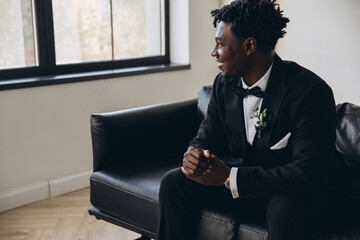 Elegant groom sitting on a couch waiting for his bride