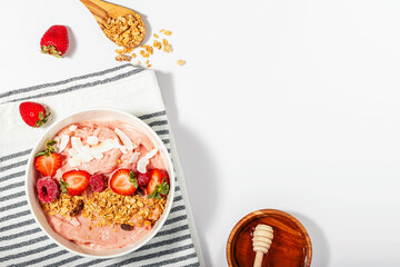 Smoothie bowl with strawberries, topped with granola and coconut chips, healthy breakfast