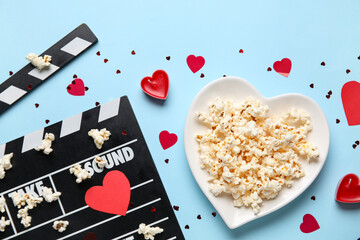 Movie clapper and popcorn with hearts decor on blue background. Valentine's Day celebration