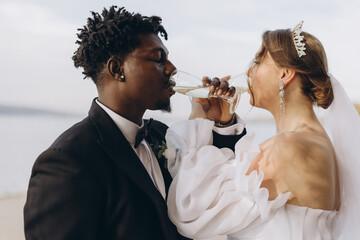 Interracial couple drinking champagne at wedding reception
