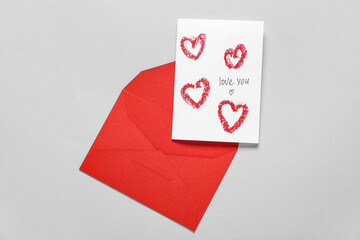 Red envelope and card with text LOVE YOU on grey background. Valentine's Day celebration