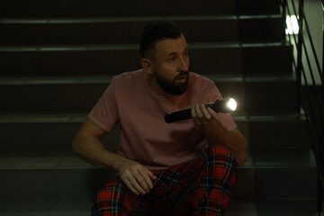 Fear of darkness. Scared man with flashlight indoors at night