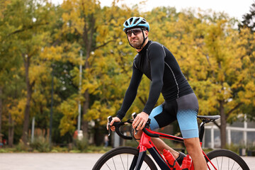 Athletic man with helmet riding bicycle outdoors