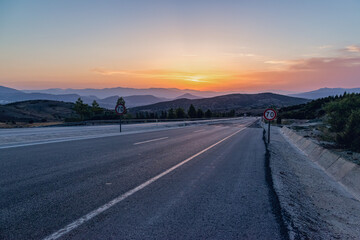 sunset on the highway, mountains in the distance