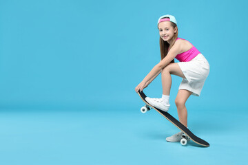 Stylish girl with skateboard on light blue background, space for text
