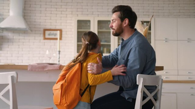 Caucasian guy man parent using laptop work happy kid daughter pupil running return home after school education smiling male father meet little girl schoolgirl dad embracing kiss child speaking family