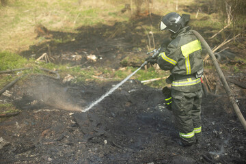 Firefighter pours water. Lifeguard with hose. Elimination of fire.