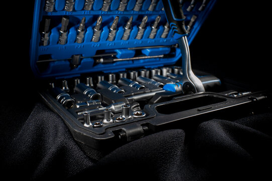 Car chrome silver tool kit with socket wrench on a dark background.