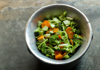 Chopped broccoli and carrots in an aluminum bowl
