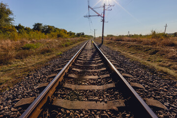 Railway tracks in the evening amidst nature with sunlight in the background