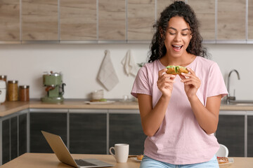 African-American woman with tasty eclair in kitchen