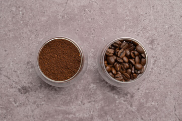Top view fresh aromatic grain and ground coffee in a small glass on a gray concrete. Copy space background, cover, backdrop, texture. Place for adding text or design