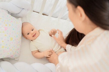 Cute little baby with mother lying in crib, closeup