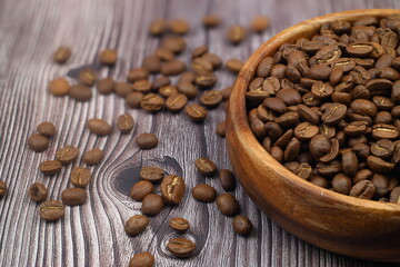 Wooden bowl with coffee beans on wooden background