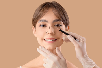 Surgeon hands drawing marks on happy woman's nose for plastic surgery against beige background