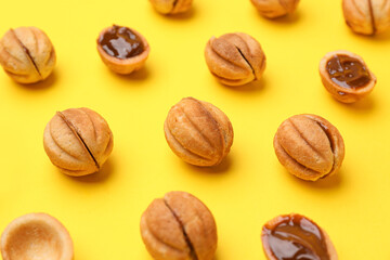 Sweet walnut shaped cookies with boiled condensed milk on yellow background