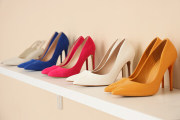 Stylish high heels on commode near beige wall, closeup