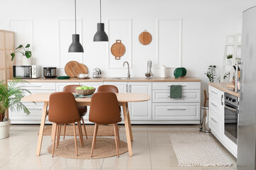 Interior of kitchen with white counters, dining table and lamps