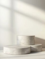 Minimalist concrete podiums with sunlight shadows on white background.