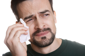 Sad man with paper tissue crying on white background