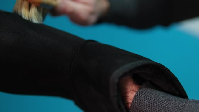 ugg boots cleaning black boots with brushes in the studio. Male brushing nubuck footwear with a small scrub brush. Theme of care for winter shoes. Washes dirty black fall booties, workshop shoes