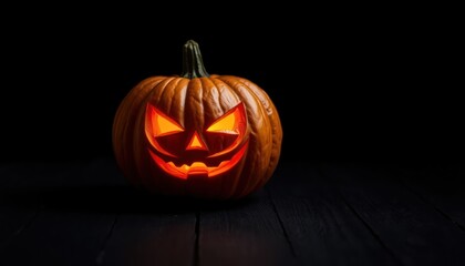 Illuminated carved pumpkin sits on dark wooden surface. Spooky jack-o-lantern glows with orange light. Halloween decoration in dark setting. Autumn holiday symbol. Festive pumpkin for spooky holiday.