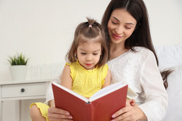 Young mother with her little daughter in bedroom