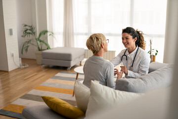 Caucasian female physician conducts friendly medical consultation with senior patient, wearing...