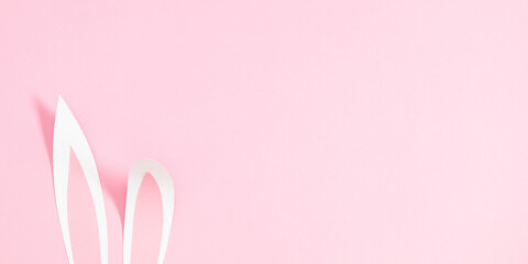 Minimalist Easter composition on pastel pink background. Cute Easter background with bunny ears. flat lay.