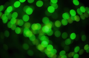 Obraz premium Green lights glow in dark night. Abstract urban scene. Dimly lit urban landscape at night. Illumination effect. Collection of green lights in darkness. Night time scene. Blurred city lights. Neon