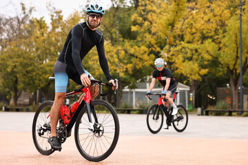 Obraz premium Athletic men with helmets riding bicycles outdoors