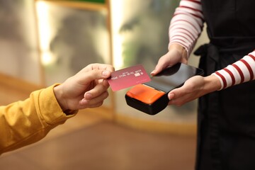 Man paying with credit card via terminal in cafe, closeup