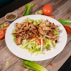 Chicken Shawarma Salad with Lettuce, Tomato, and Pickles on a White Plate

