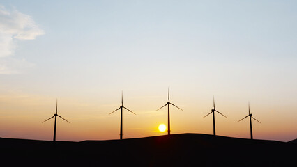 Wind power plant towers in mountains at sunset. Windmill farm. Sustainable energy production. Green energy, clean power, clean energy concept.	
