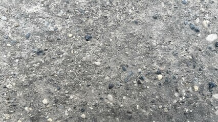 Textured surface of concrete with pebbles and small stones in daylight