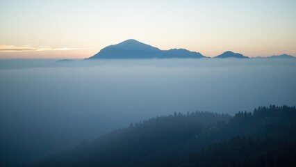 Obraz premium Misty Mountain Sunrise: Serene Peak Above the Clouds