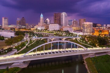 Obraz premium Evening cityscape of downtown Columbus, OH, featuring the Scioto Mile and a modern bridge. Urban park and river views. MAIN ST. BRIDGE, COLUMBUS, OHIO, UNITED STATES