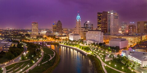 Obraz premium Night view of downtown Columbus, Ohio. Urban skyline, riverfront park, and illuminated bridges. Beautiful city at night. DOWNTOWN, COLUMBUS, OHIO, UNITED STATES
