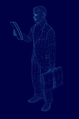 Man is standing in front of a blue background, holding a book in his hand. Concept of focus and concentration, as the man is reading the book intently