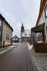 Obraz premium Blick durch eine Gasse auf die verschneite Erlöserkirche in Schmiedefeld am Rennsteig, Stadt Suhl, Thüringen, Deutschland